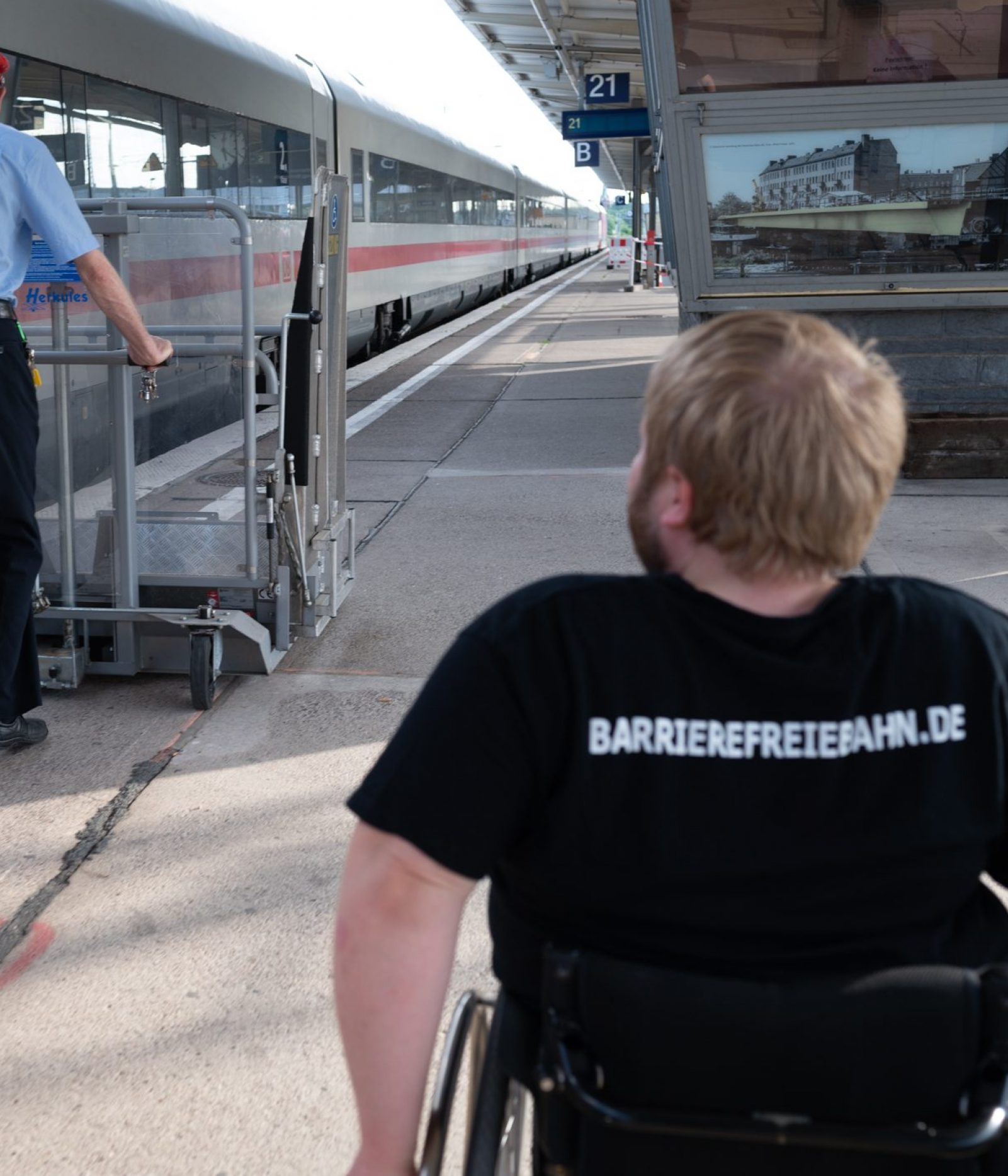 Mensch im Rollstuhl folgt Bahnmitarbeiter mit Hublift an einem Bahnsteig mit einem ICE Foto: Jacqueline Hirscher
