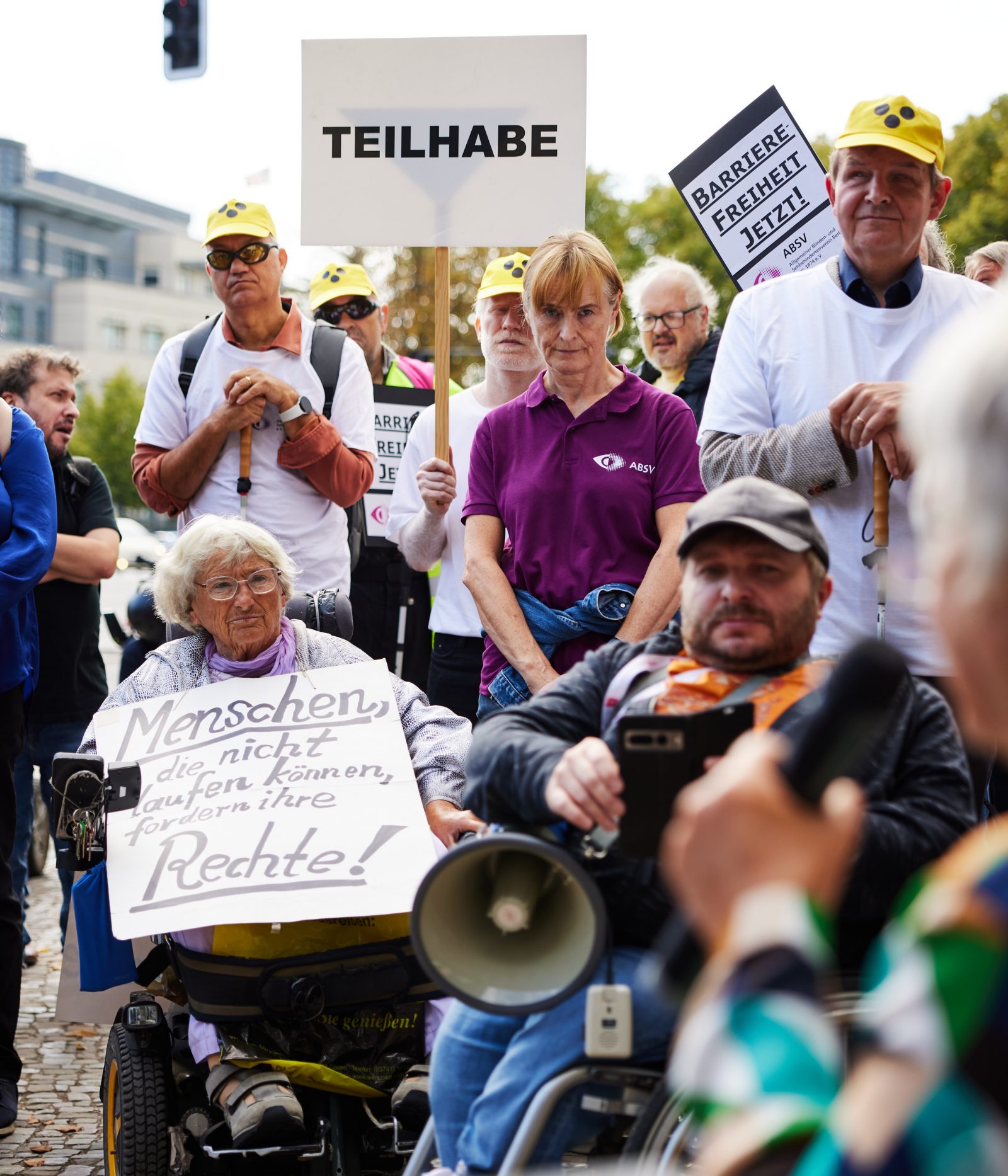Demonstrierende halten eine Kundgebung mit Megafon und Protestschildern